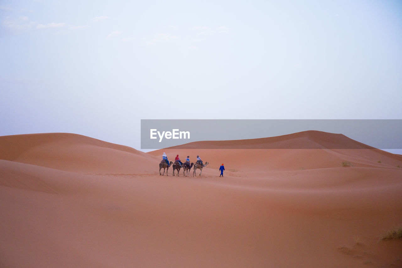 People walking in desert against sky