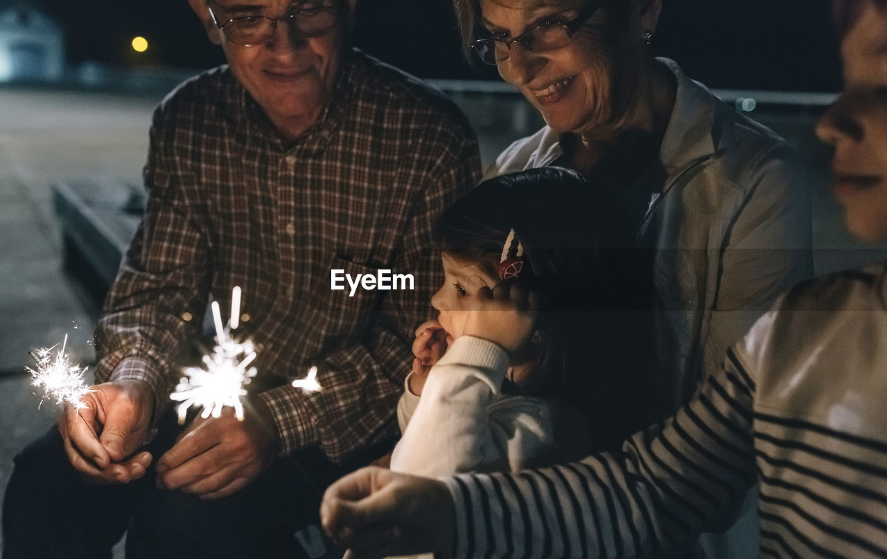 Grandparents with grandchildren holding sparklers at night