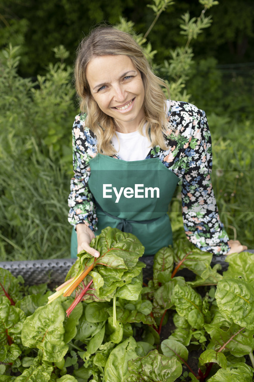 portrait of smiling woman standing against plants
