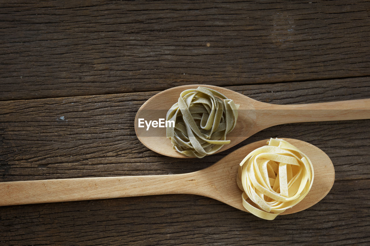Close-up of tagliatelle pasta in wooden spoons on table