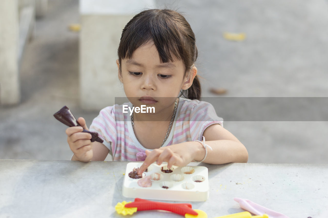 Close-up of cute girl playing with childs play clay at table outdoors