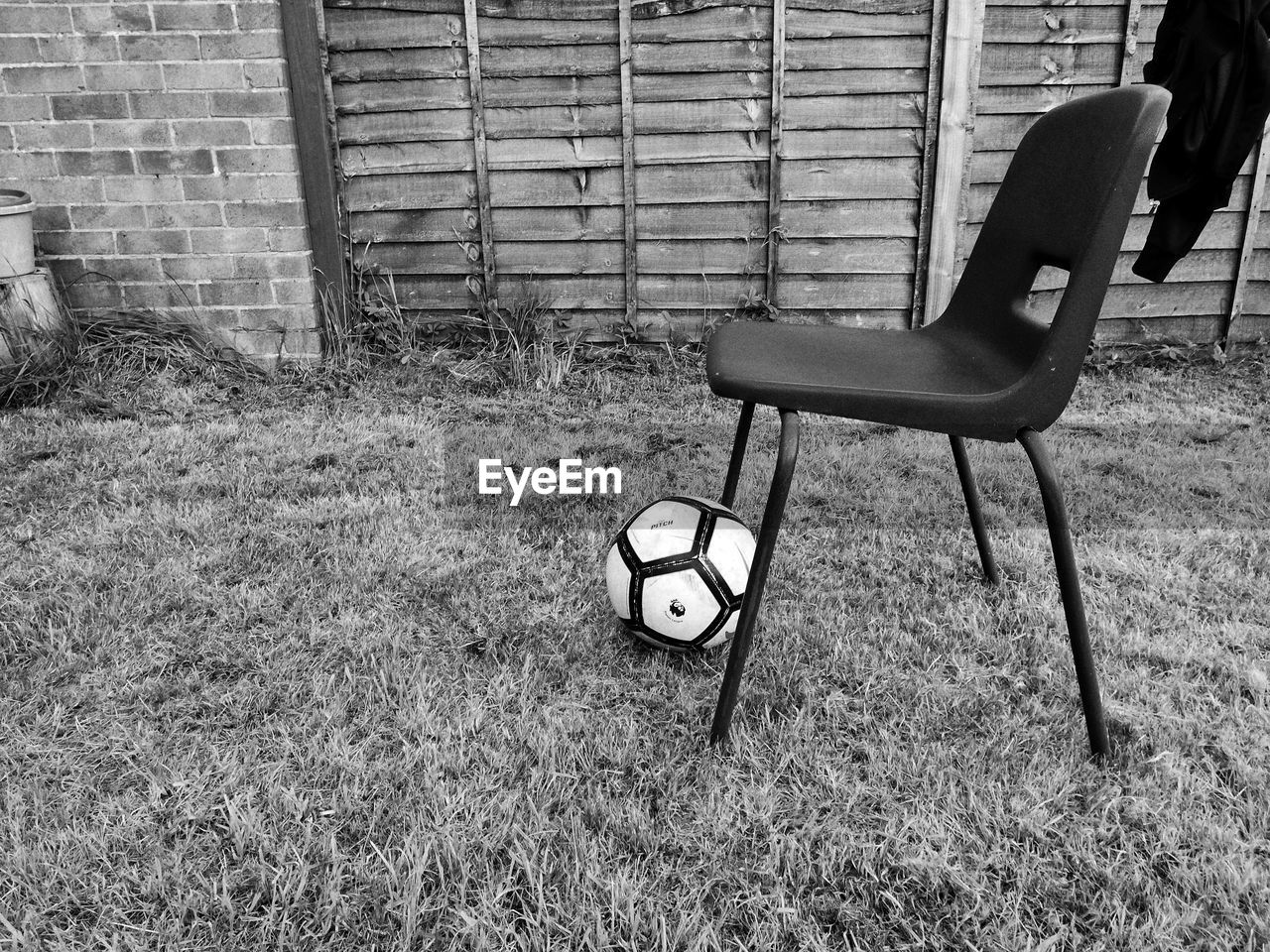 EMPTY CHAIR ON FIELD BY ABANDONED BUILDING
