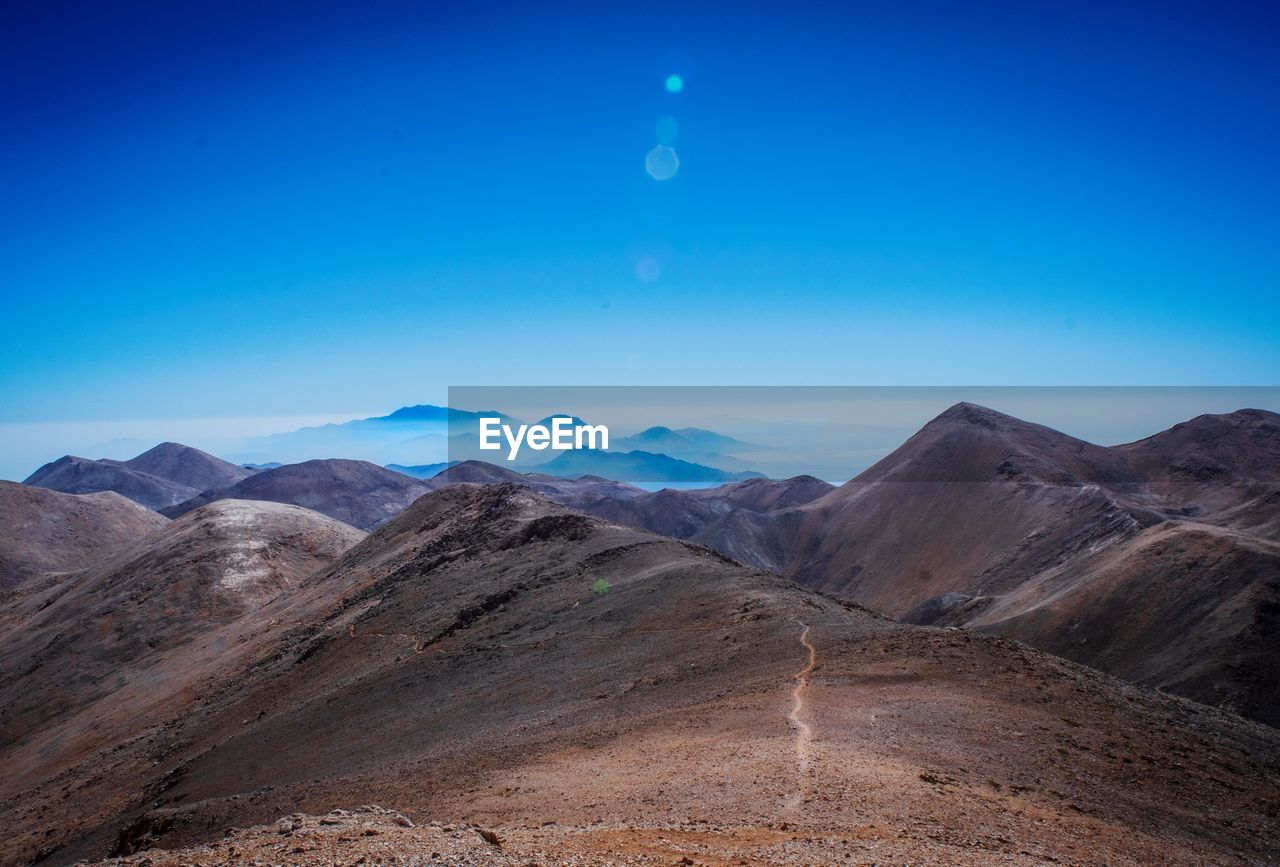 Scenic view of arid landscape against clear blue sky