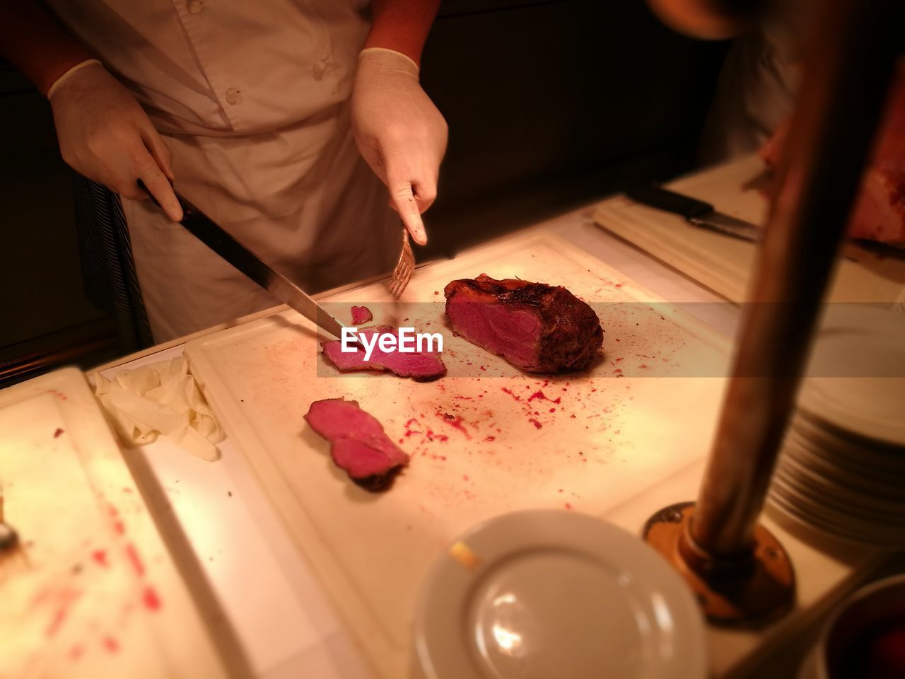 Close-up of man cutting meat in restaurant