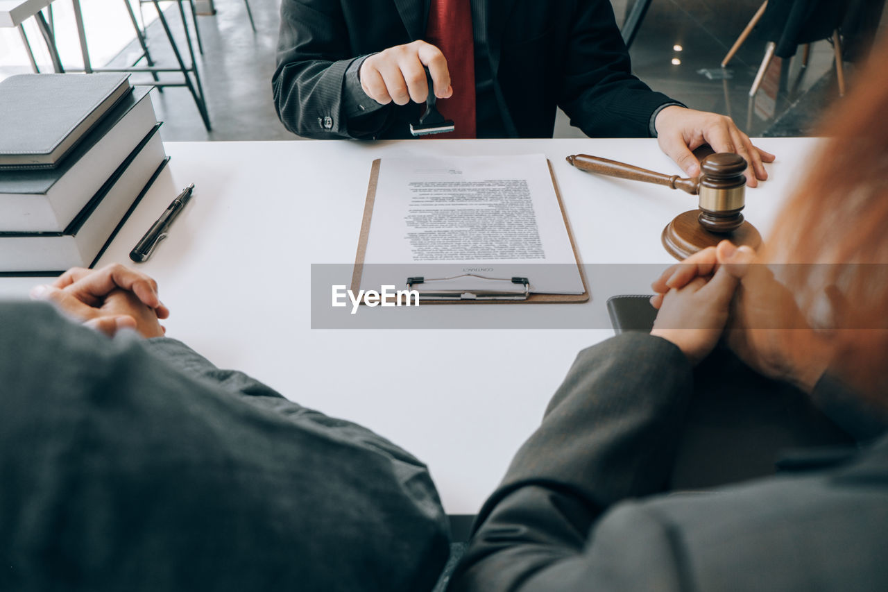 Midsection of lawyer holding rubber stamp over document on desk