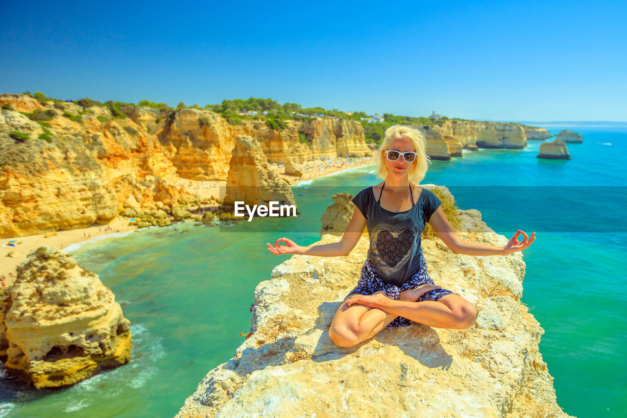 Woman doing yoga on rock at beach