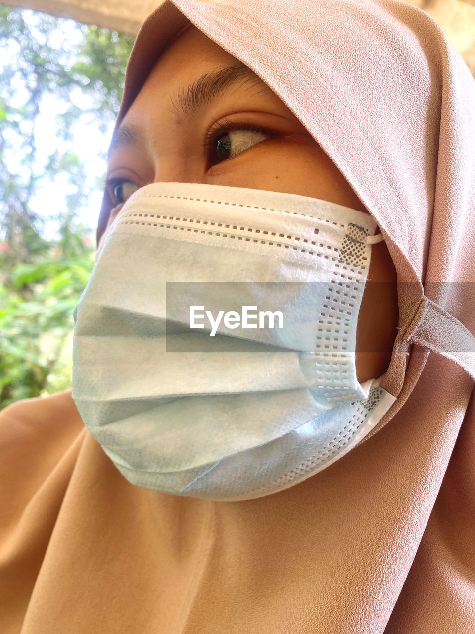 Close-up young woman wearing mask looking away