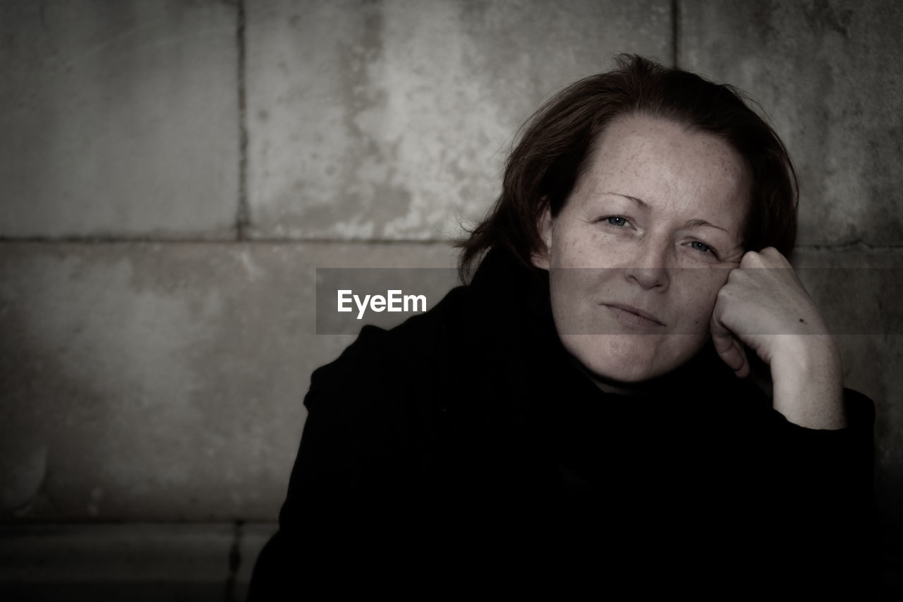 Portrait of woman against wall outdoors