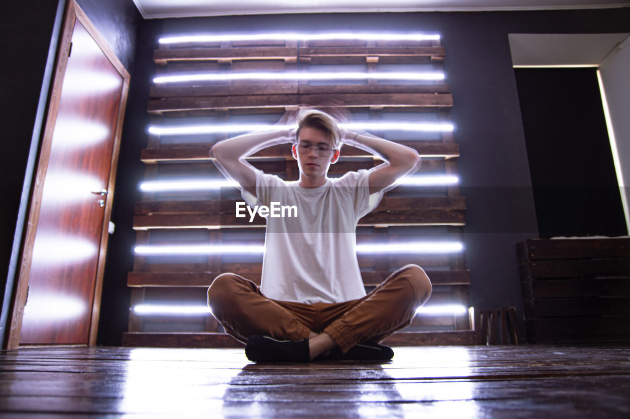 Full length of man meditating while sitting on floor