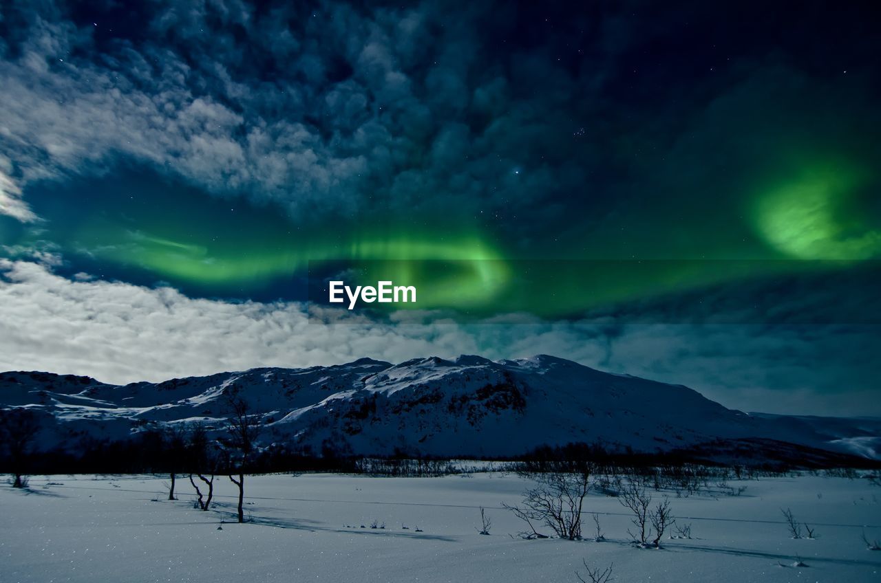 SCENIC VIEW OF SNOWCAPPED MOUNTAINS AGAINST DRAMATIC SKY AT NIGHT