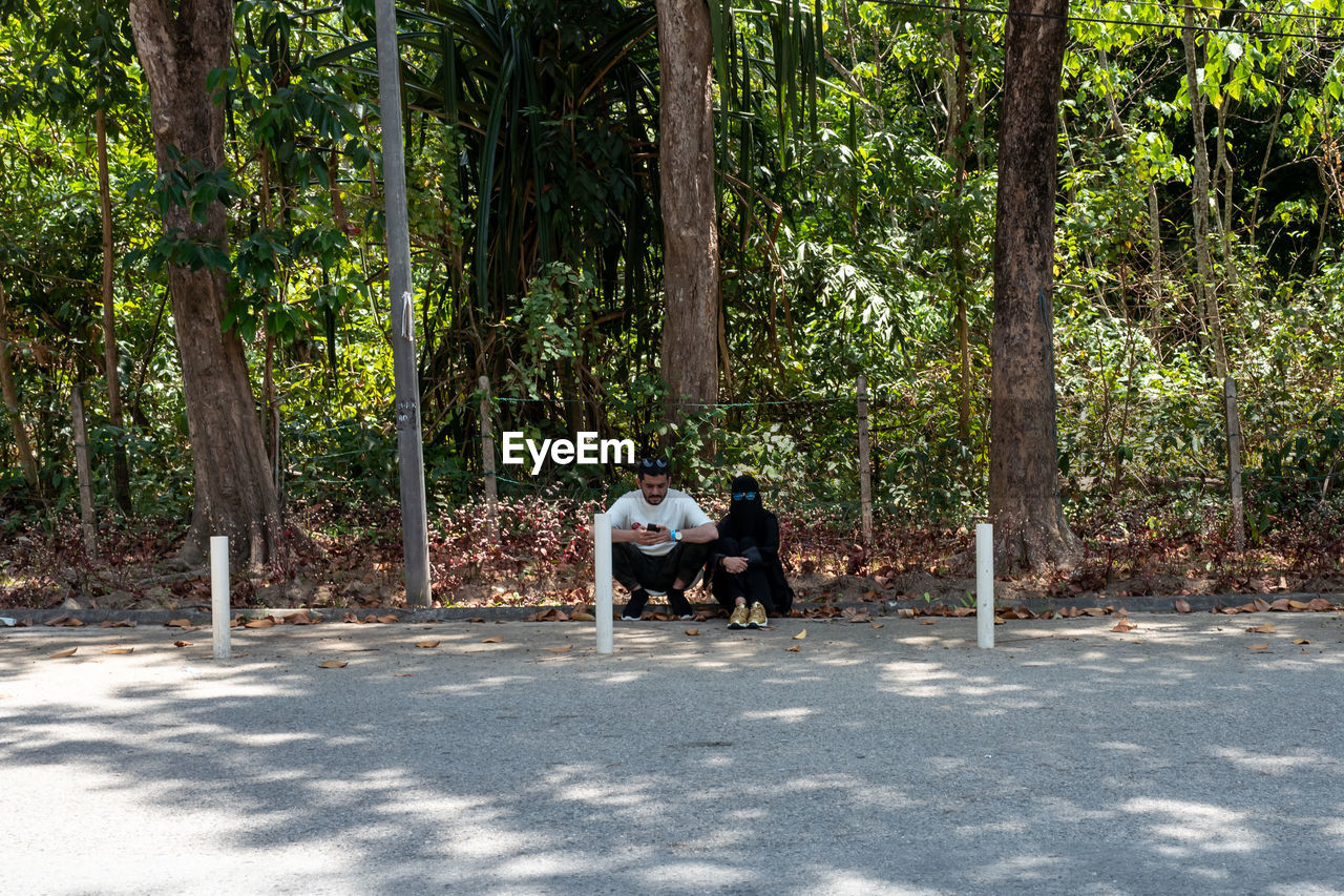 REAR VIEW OF A MAN AND WOMAN WALKING ON ROAD