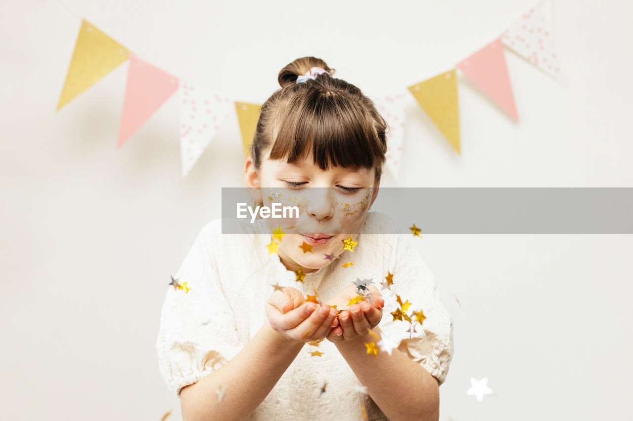 Adorable little girl blows glitter off her hands. holiday, birthday, party for kids. happy childhood