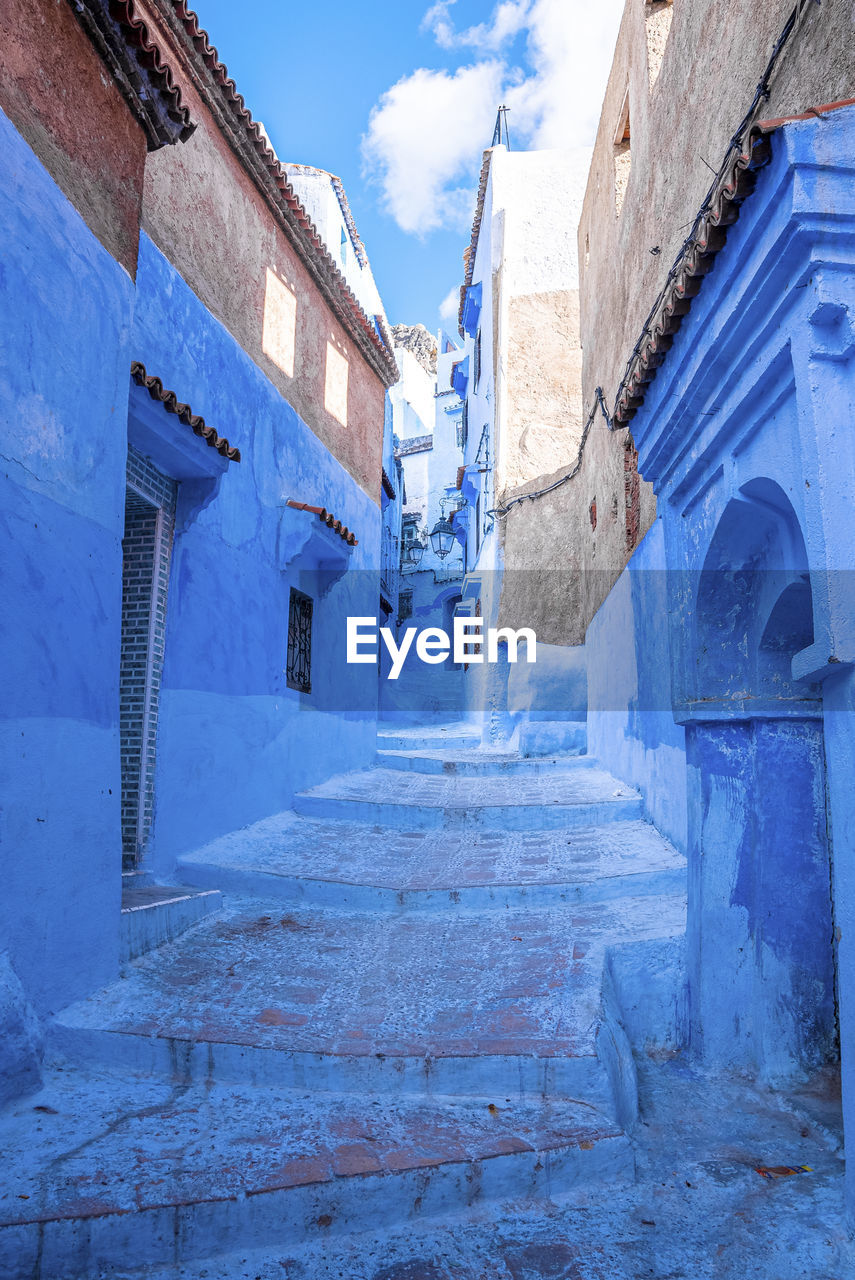 Narrow alley of blue town with staircase leading to residential structures on both side