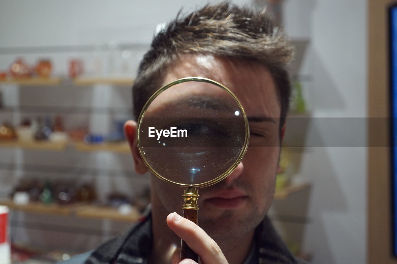 Close-up of man looking through magnifying glass at store