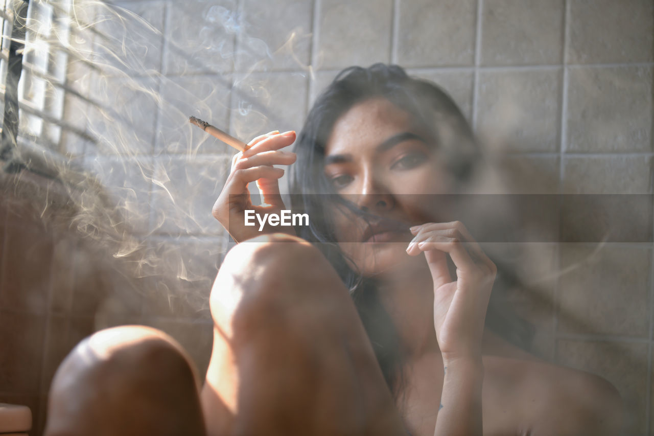 Portrait of young woman smoking in bathroom