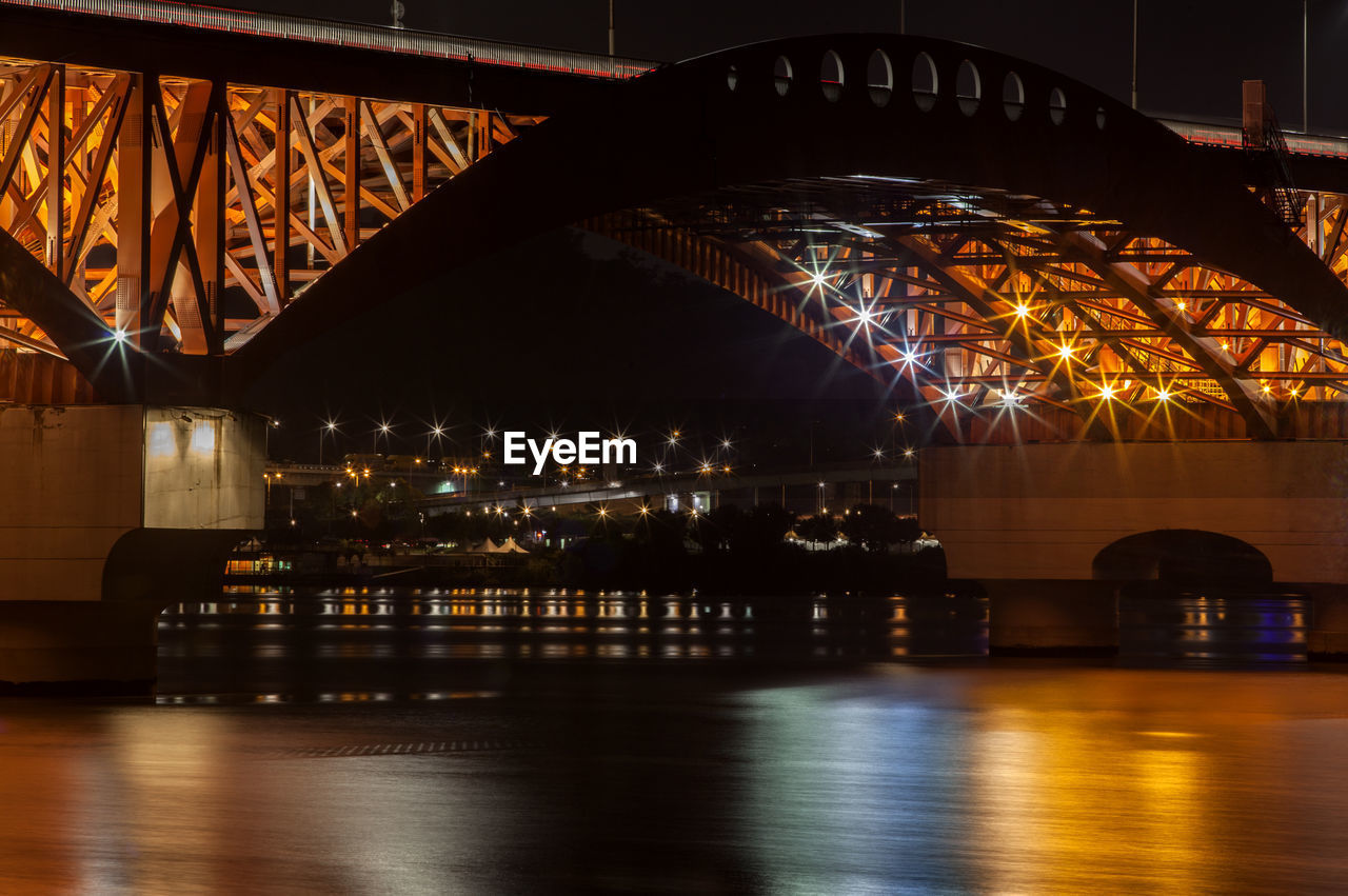 Illuminated bridge over river at night