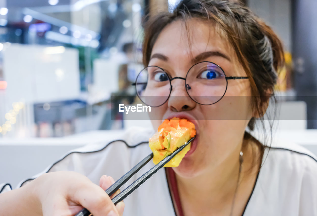 Close-up portrait of woman eating food at restaurant