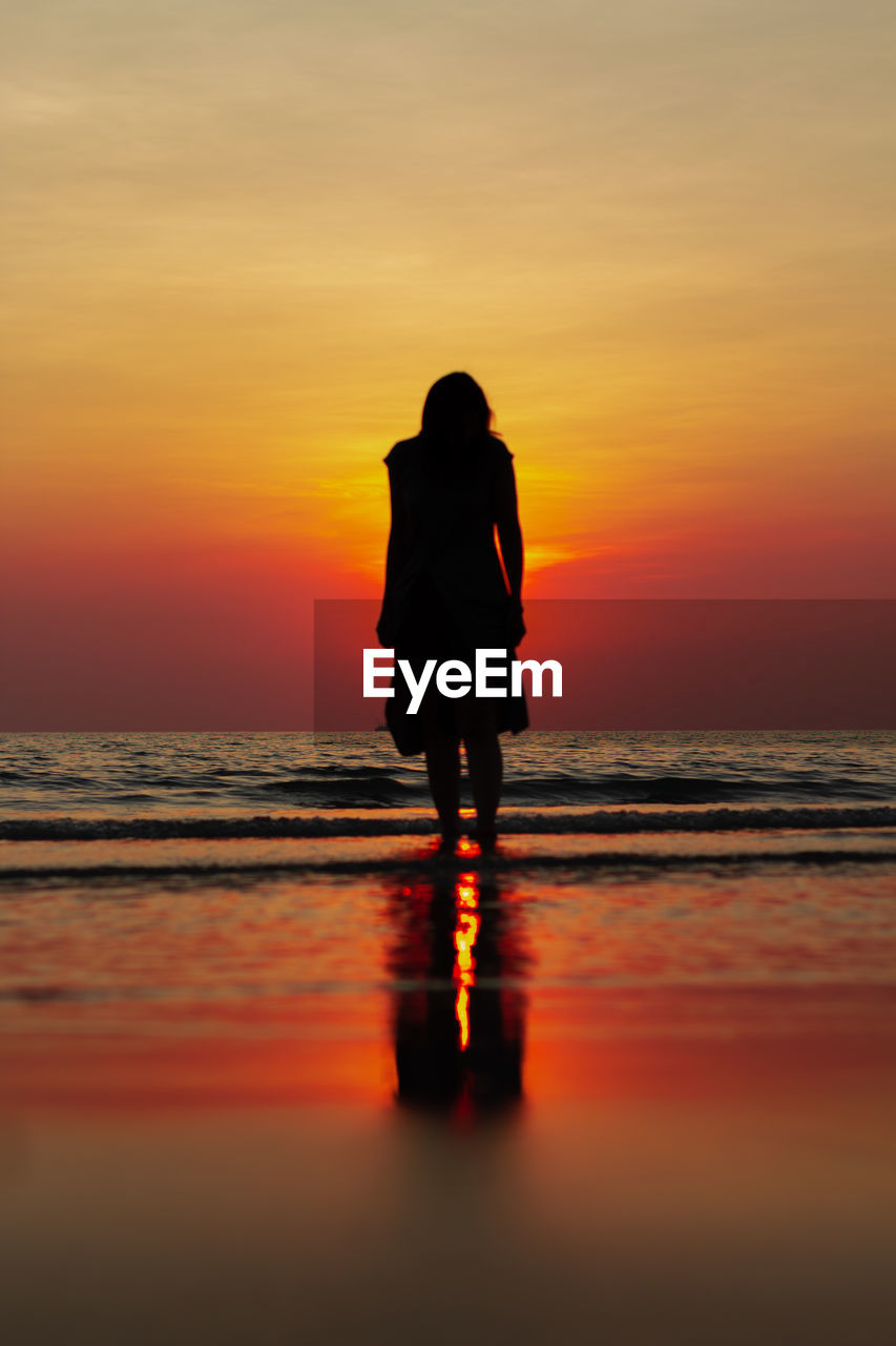 Woman standing at beach during sunset