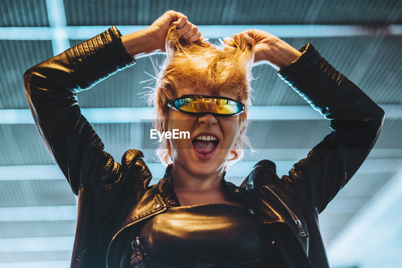 Happy young woman wearing smart glasses with hands in hair