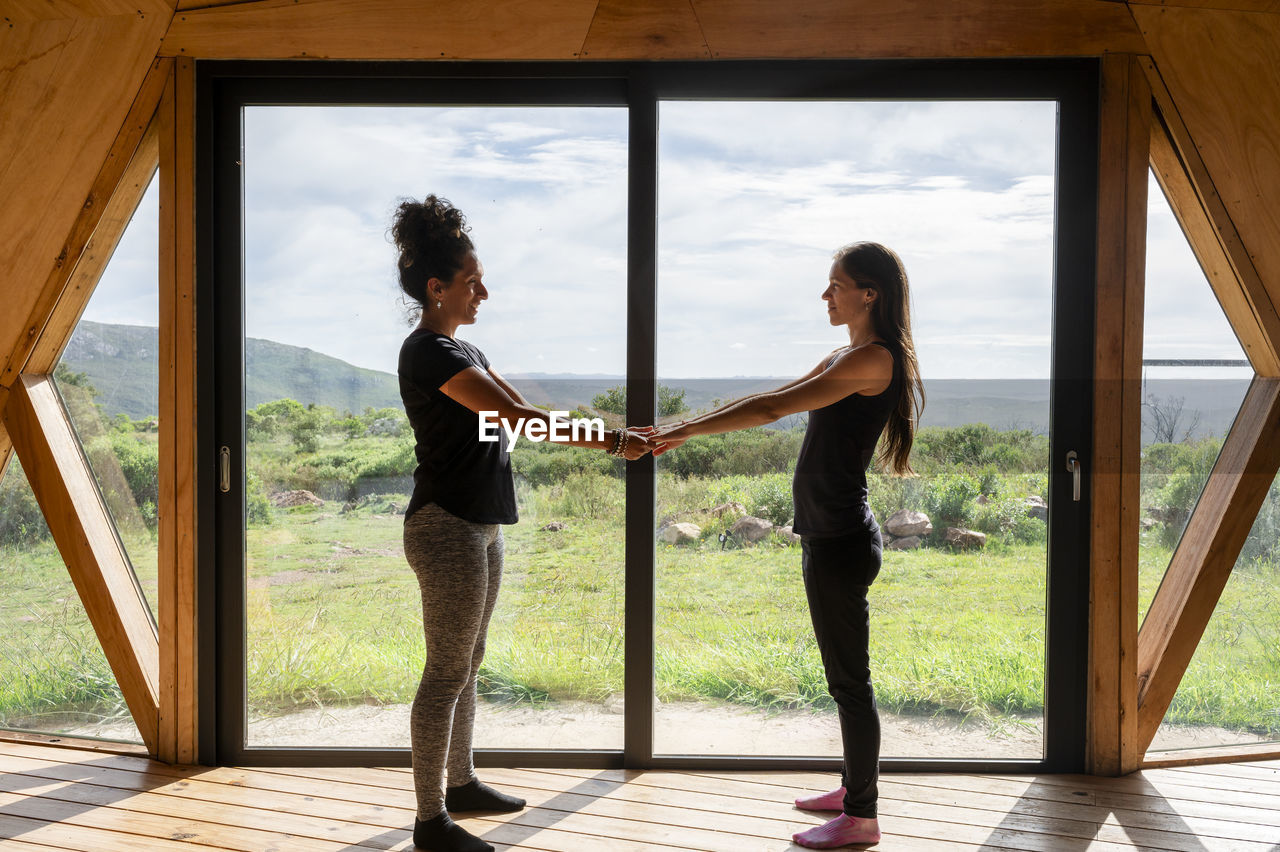 Female couple holding hands while relaxing in a wooden dome tent.