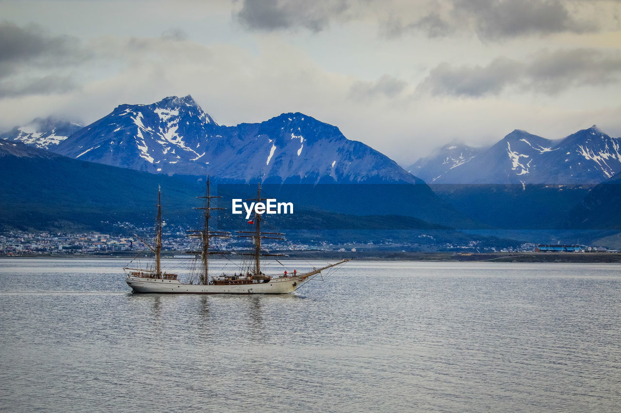 SAILBOAT ON SNOWCAPPED MOUNTAIN AGAINST SKY