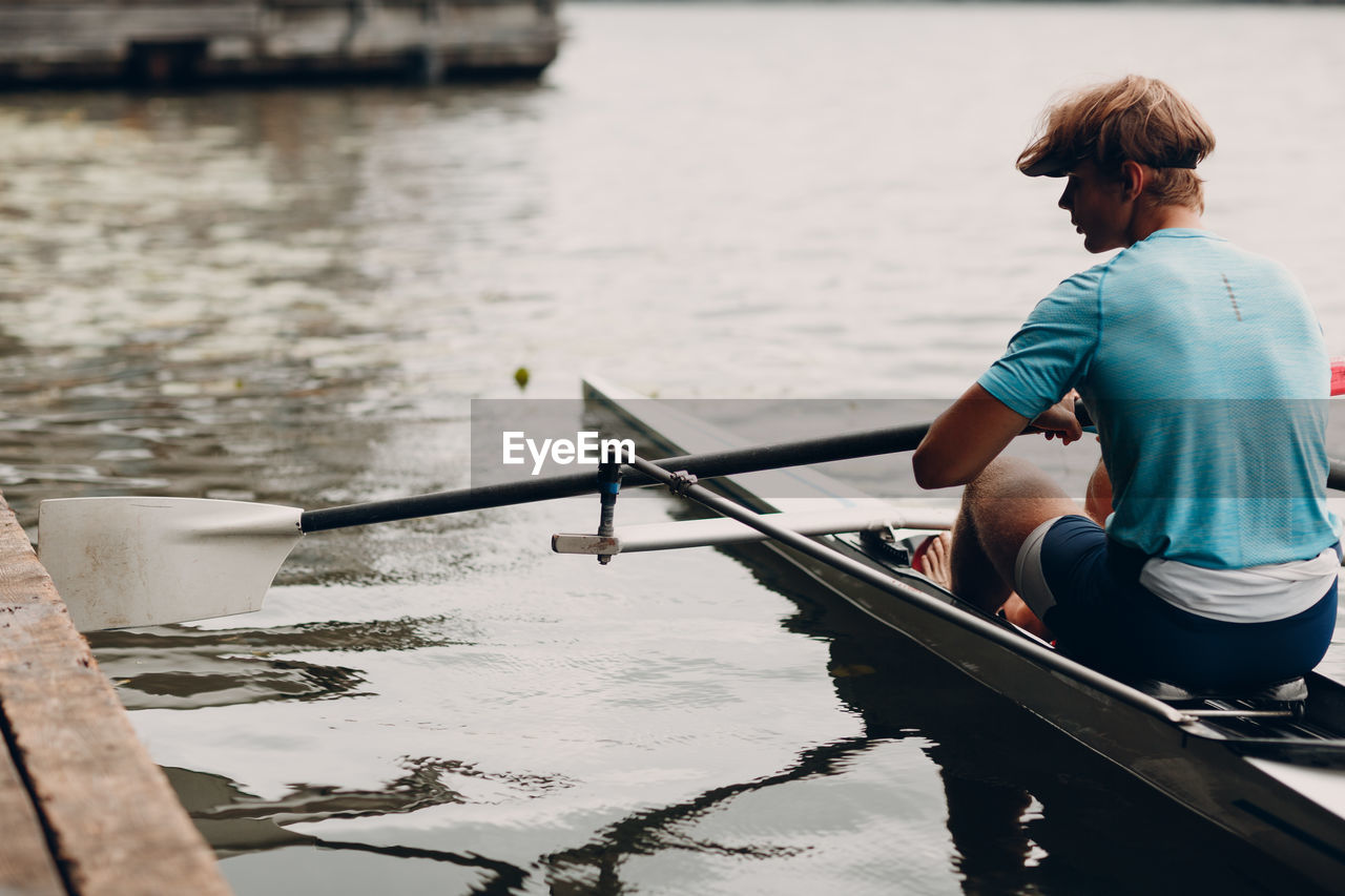 Rear view of man sitting on boat in lake