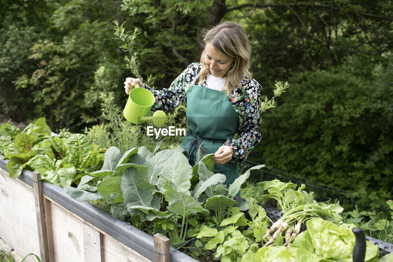 REAR VIEW OF WOMAN SITTING ON PLANT