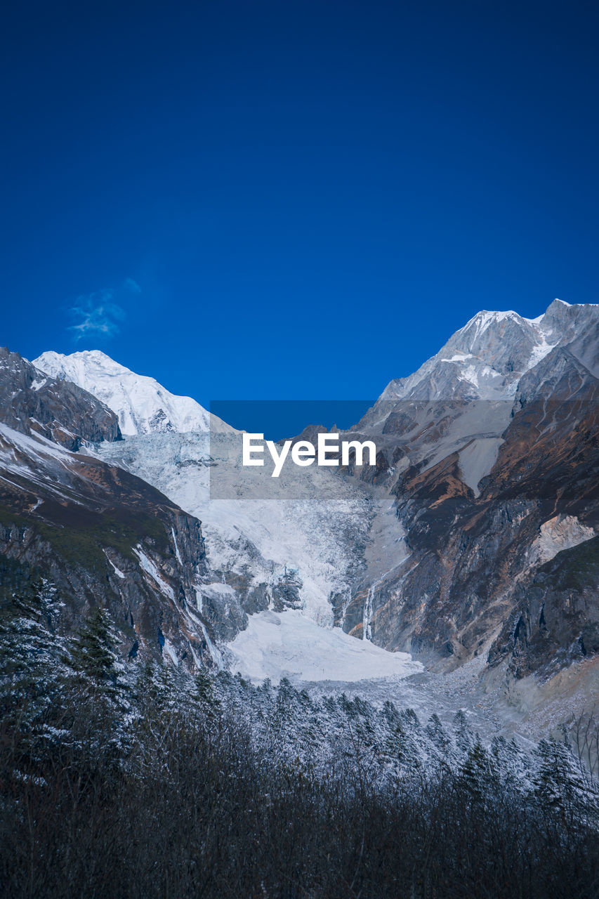 Scenic view of snowcapped mountains against clear blue sky