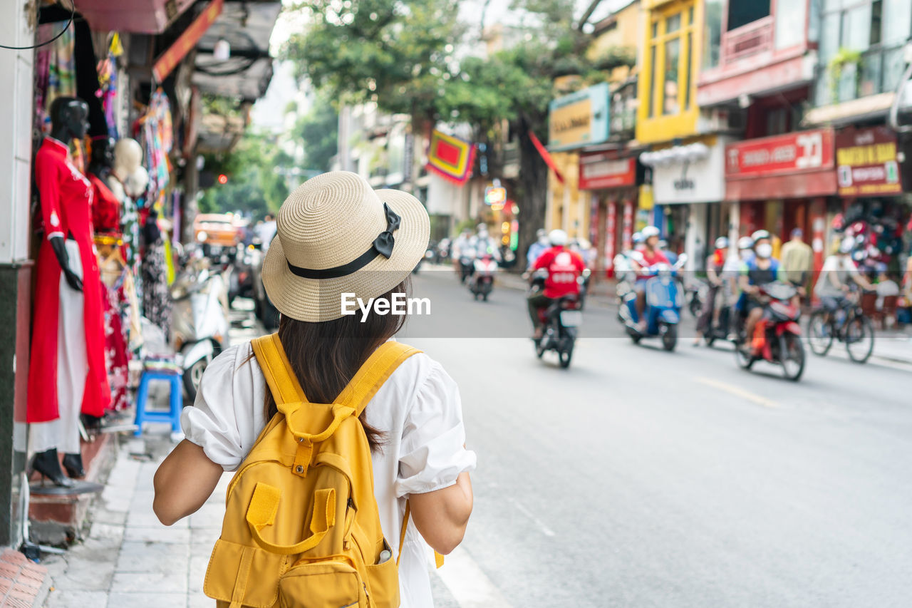 rear view of woman standing on street in city