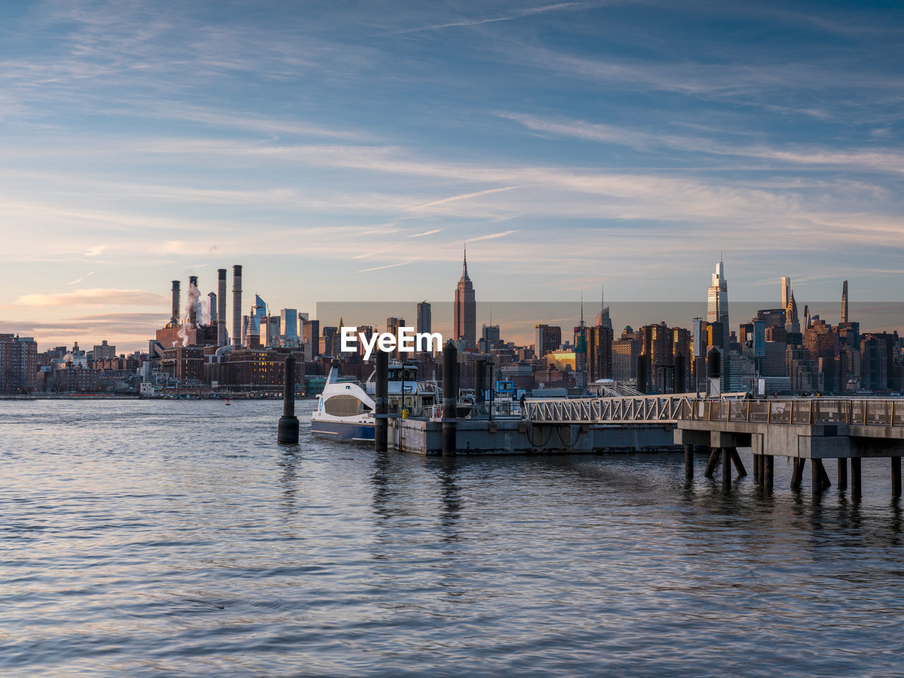 Sunset over east river midtown manhattan skyline and north 5th street pier at brooklyn