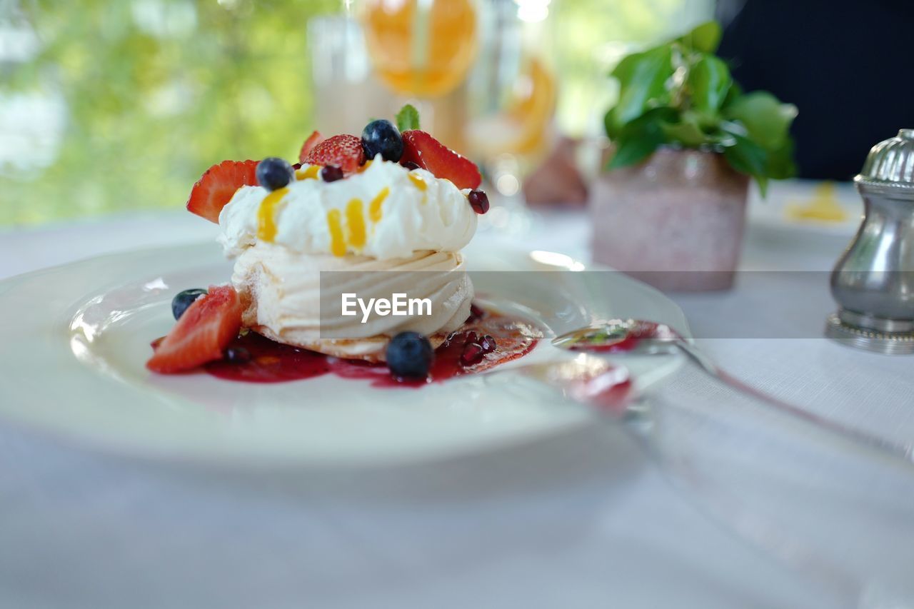 Pavlova dessert with fresh berried on a sun lit restaurant table 