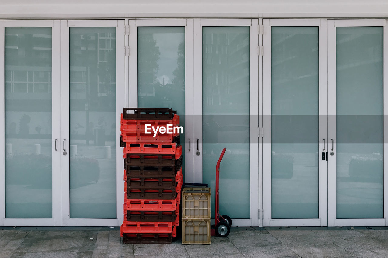 Crates on footpath by glass door