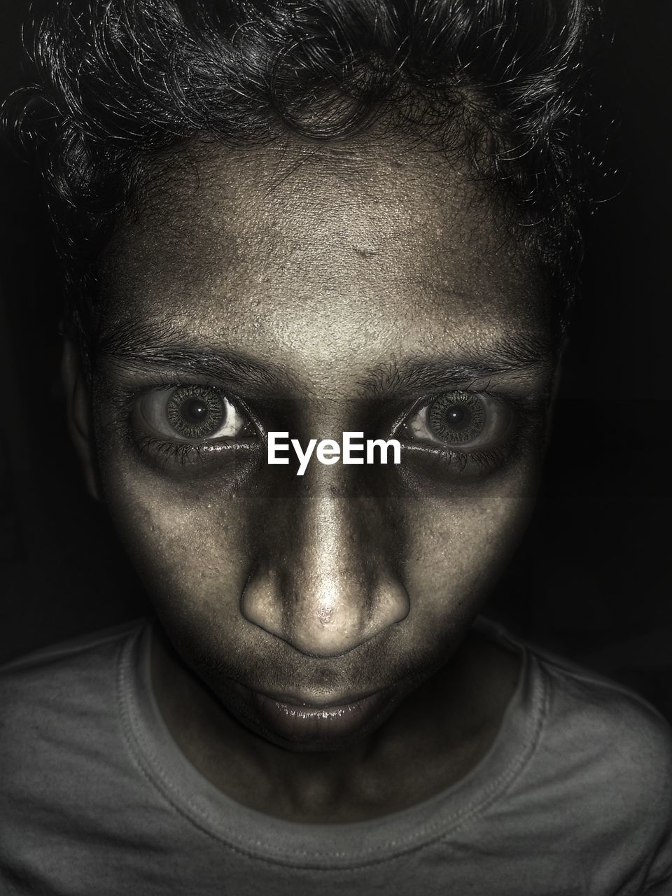 Close-up portrait of boy with spooky eyes against black background