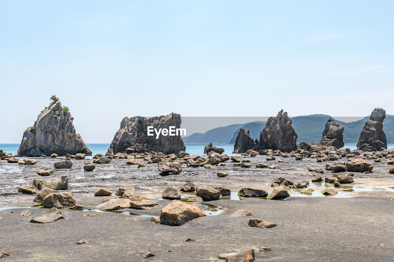 PANORAMIC VIEW OF ROCKS AND SEA AGAINST CLEAR SKY