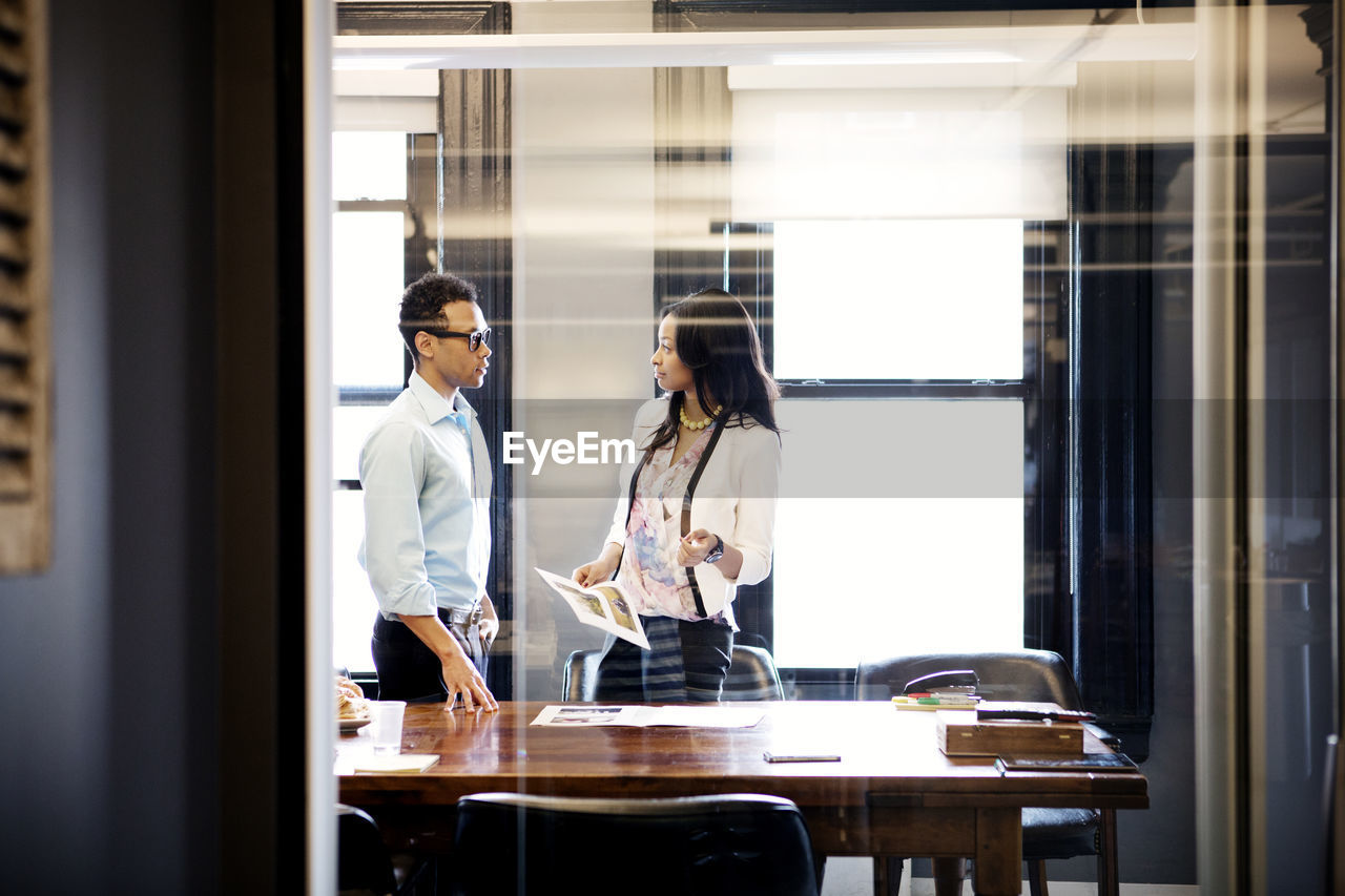 Businesswoman talking to colleagues while standing in office