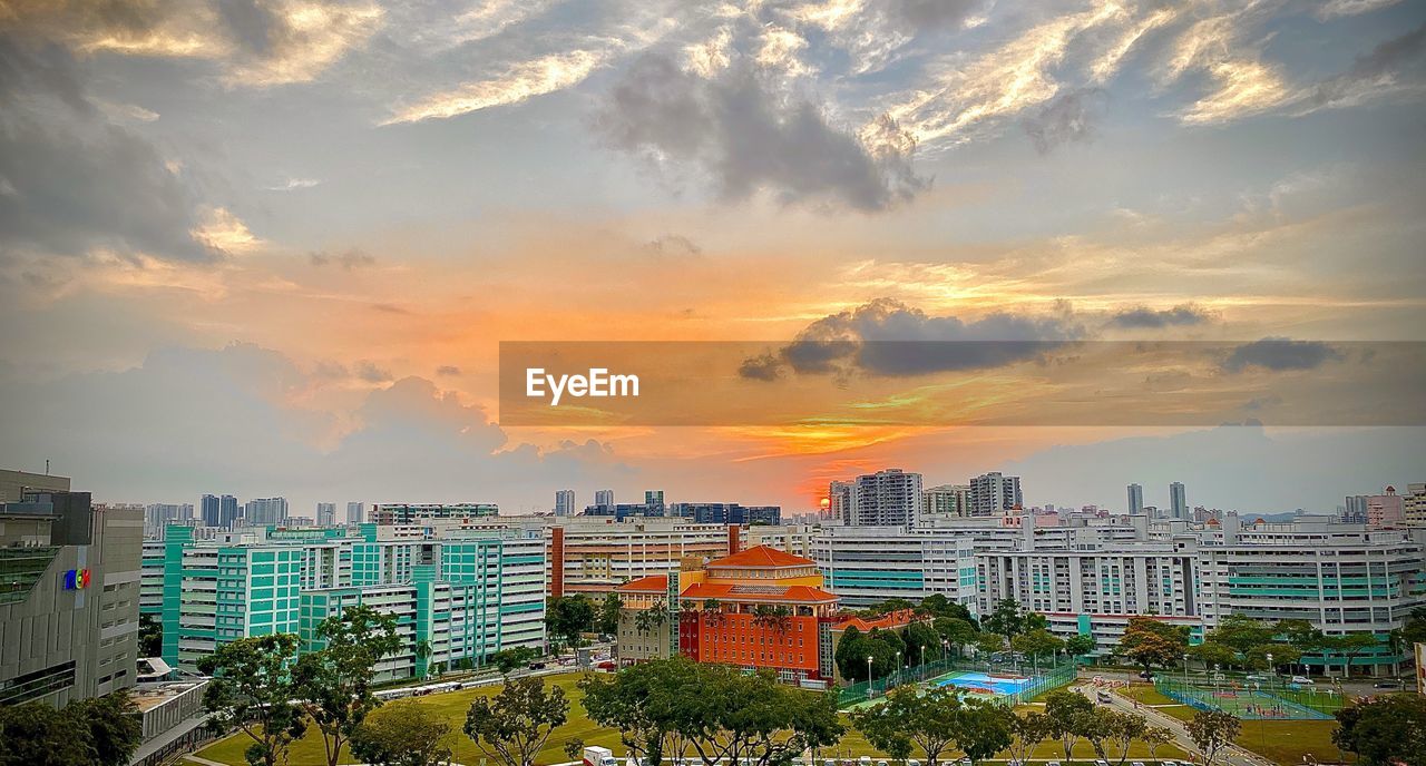 HIGH ANGLE VIEW OF BUILDINGS IN CITY AGAINST SKY DURING SUNSET