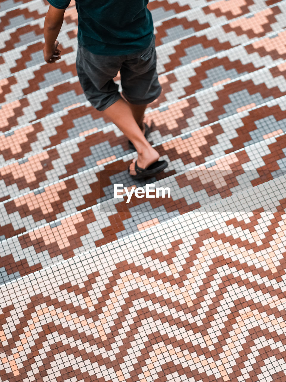 A boy walking down a classic design mosaic steps