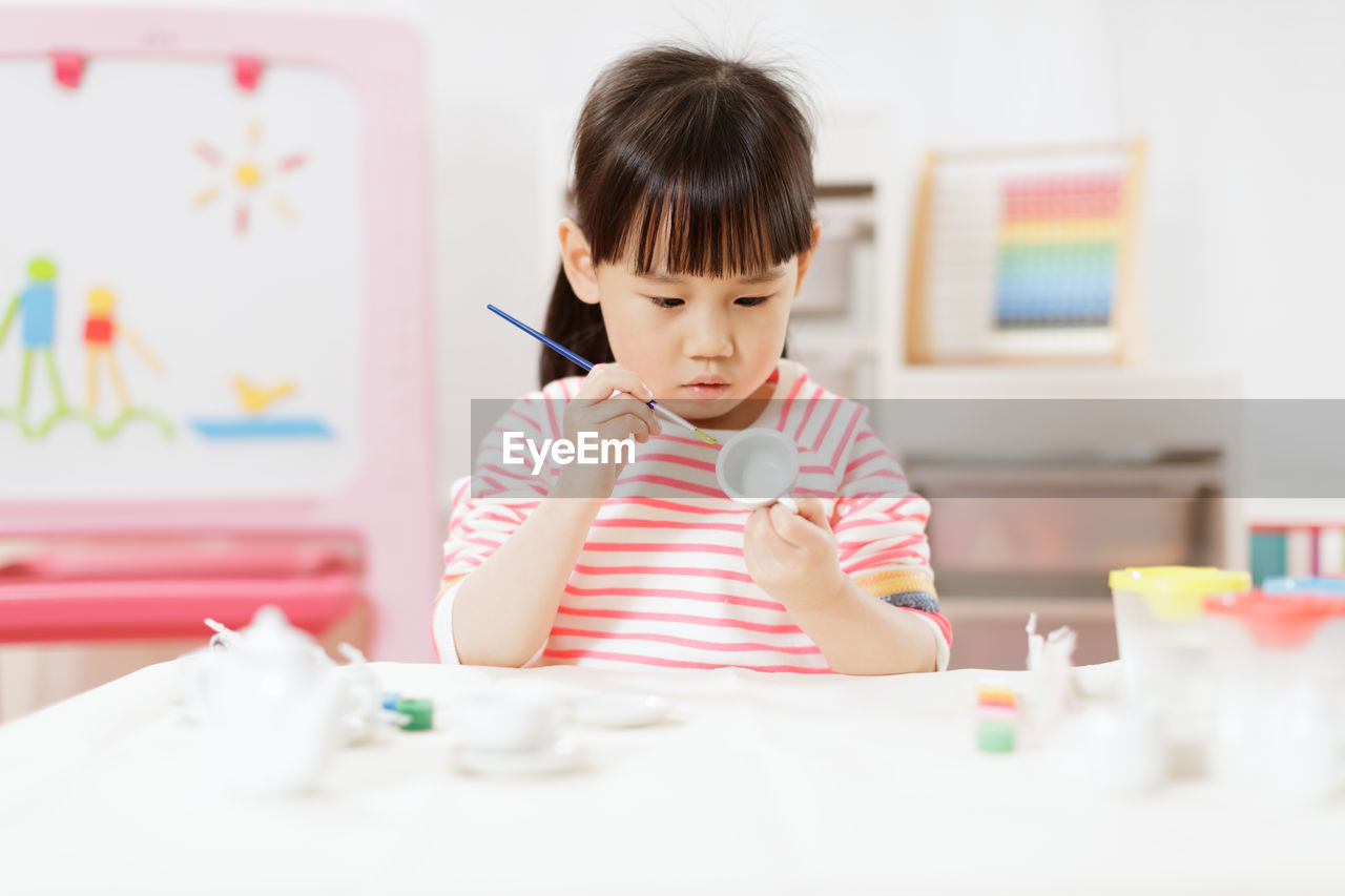 Young girl decorating hand made craft for homeschooling