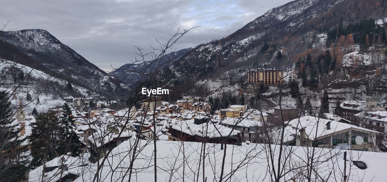 SNOW COVERED HOUSES AND TREES AGAINST SKY