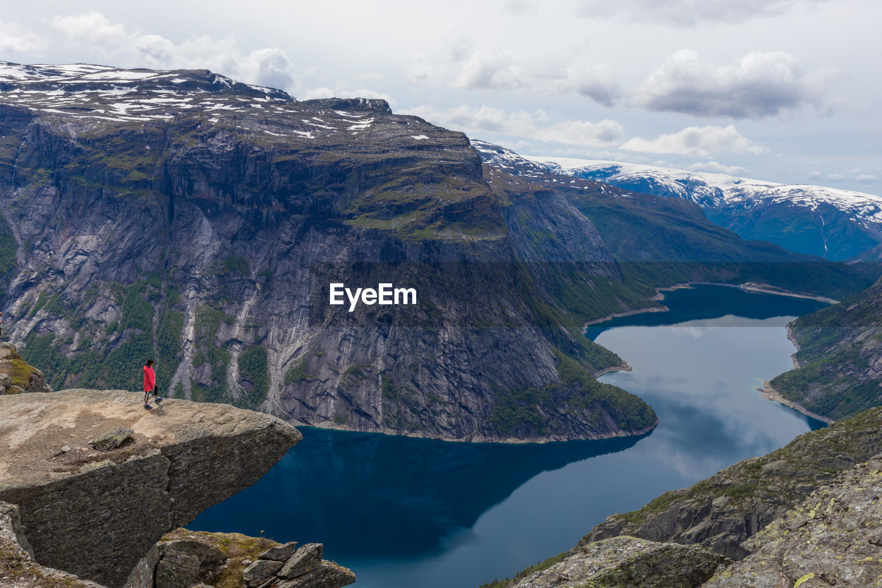 Woman standing on edge of cliff at trolltunga mountain in norway.