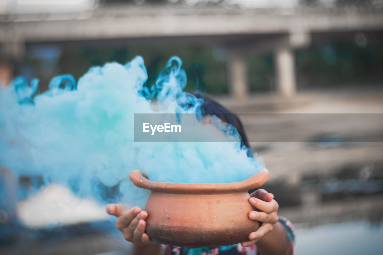 Woman holding smoke emitting from pottery