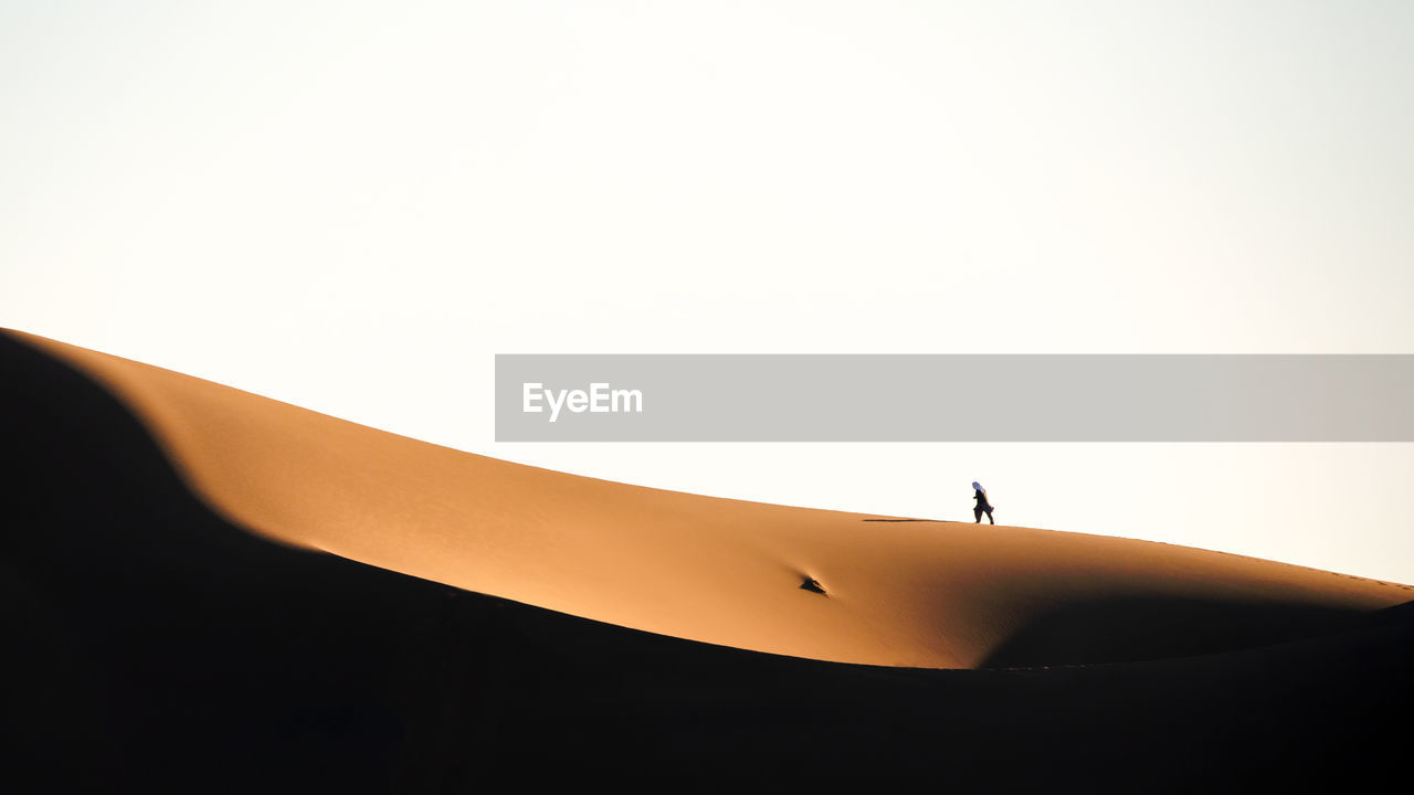 Nature and landscapes of dasht e lut or sahara desert with one man walking on a sand dunes