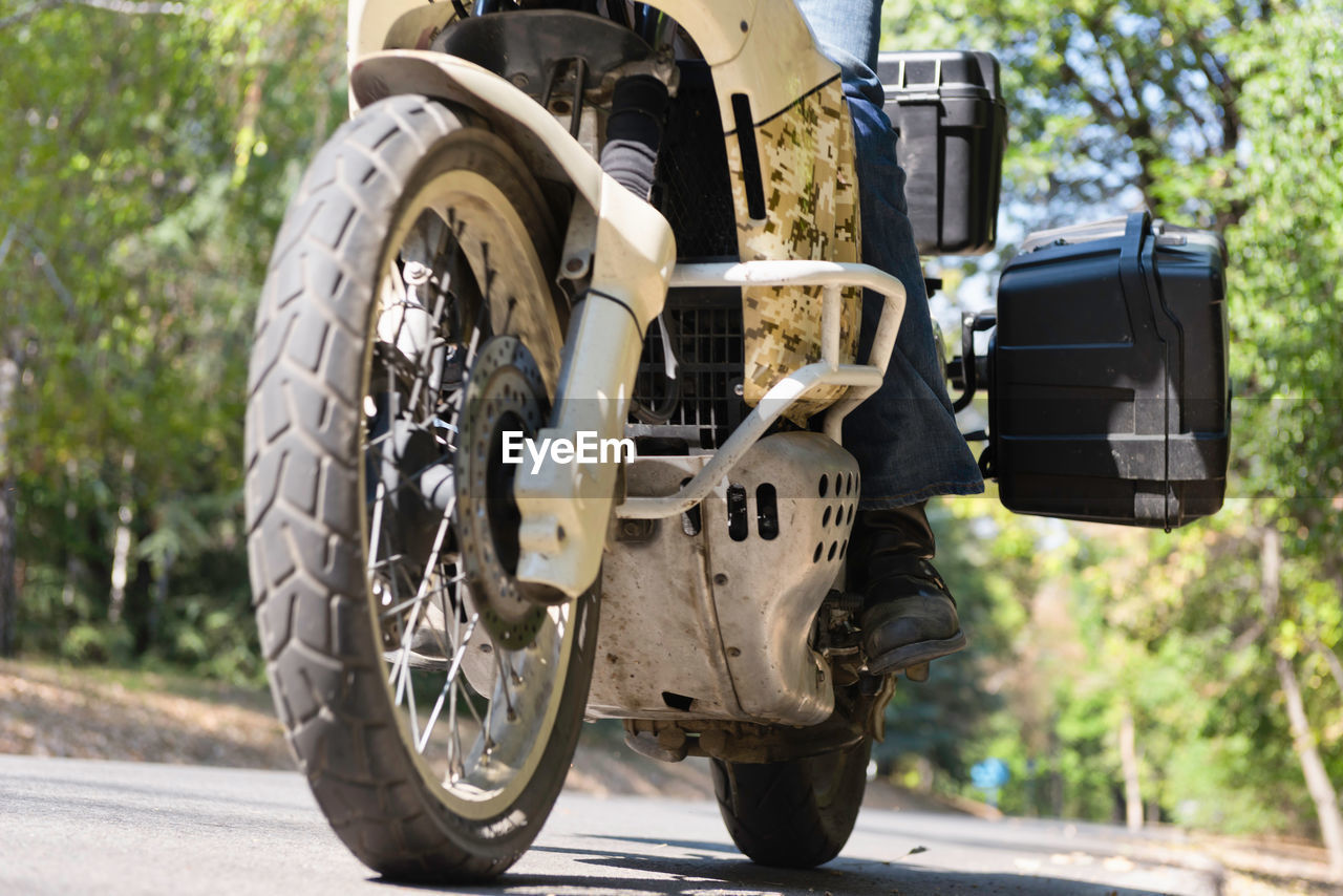 Low section of man riding motorcycle on road