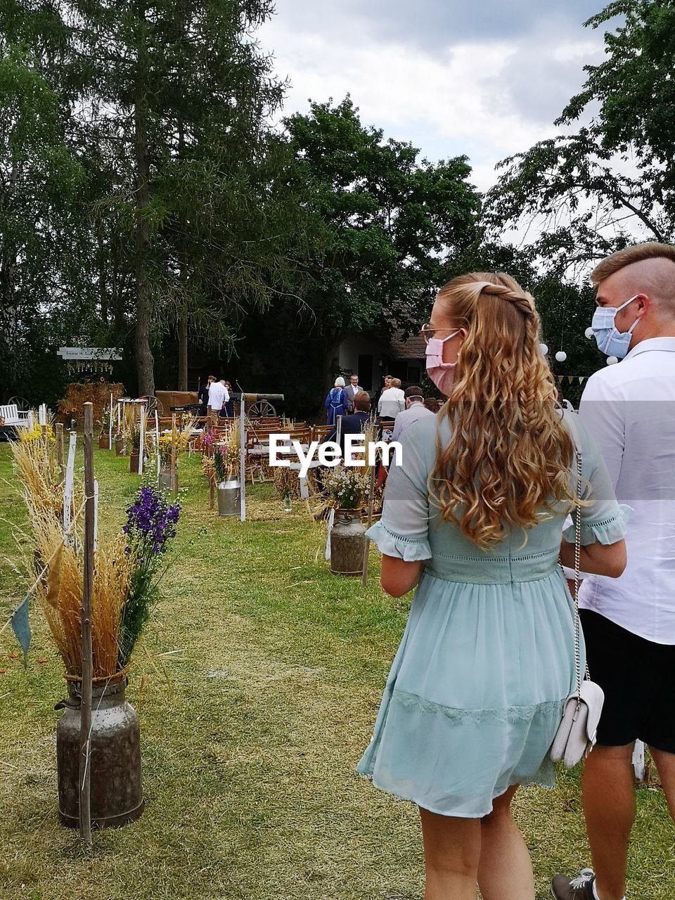 Rear view of couple standing on field against trees