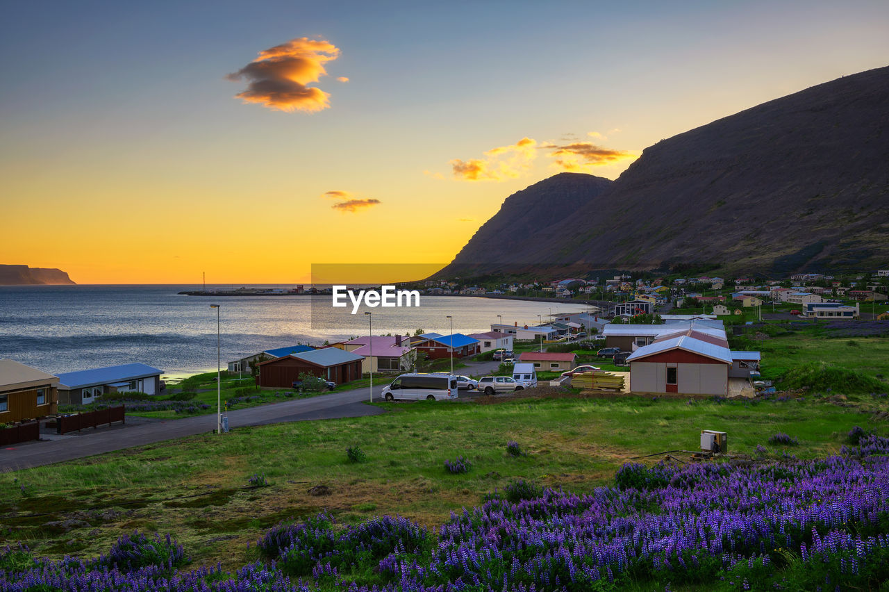 SCENIC VIEW OF SEA BY BUILDINGS AGAINST SKY AT SUNSET