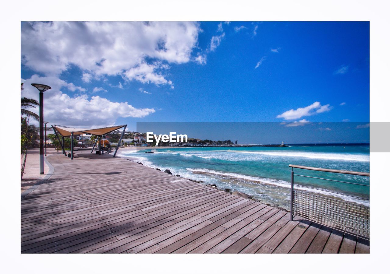 EMPTY CHAIRS BY BEACH AGAINST BLUE SKY