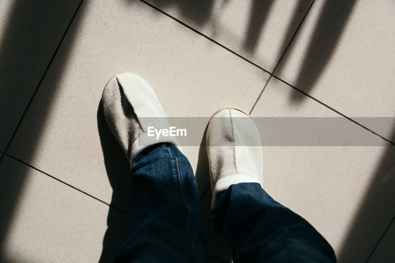 Low section of man standing on tiled floor