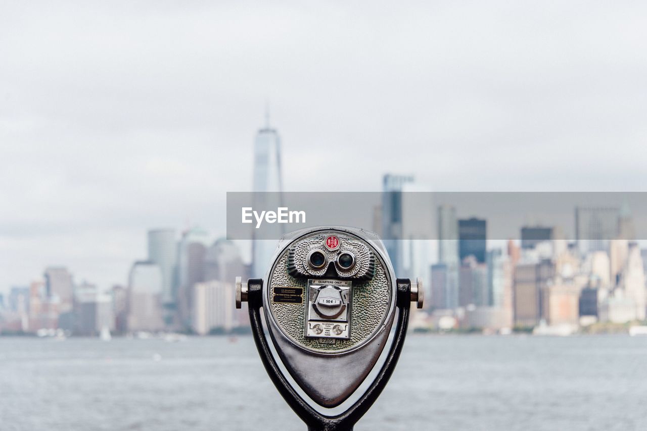 CLOSE-UP OF COIN-OPERATED BINOCULARS AGAINST CITYSCAPE IN SEA