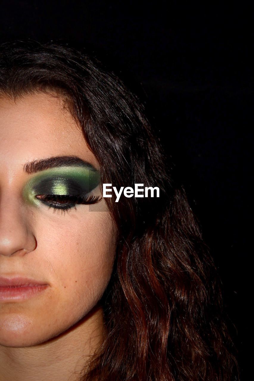 Cropped image of young woman eye against black background