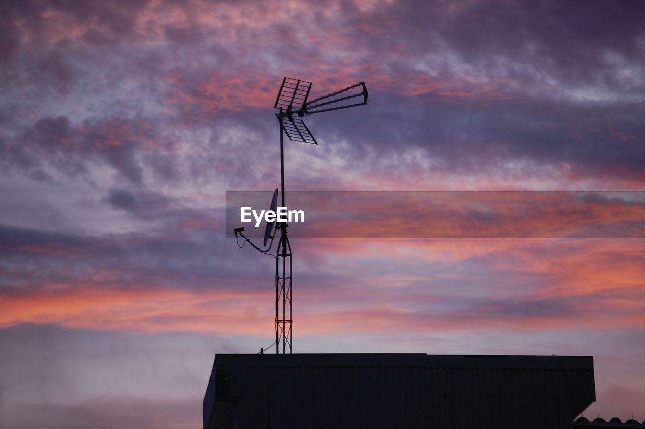 Low angle view of silhouette communications tower against sky during sunset